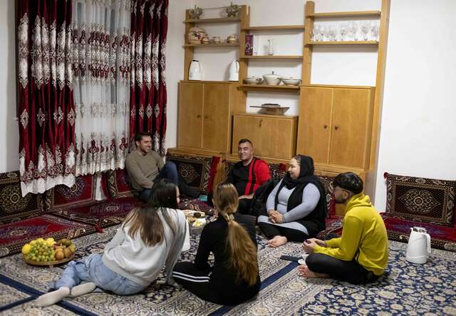 Afghanische Familie in Deutschland beim gemeinsamen Abendessen in traditioneller Einrichtung.