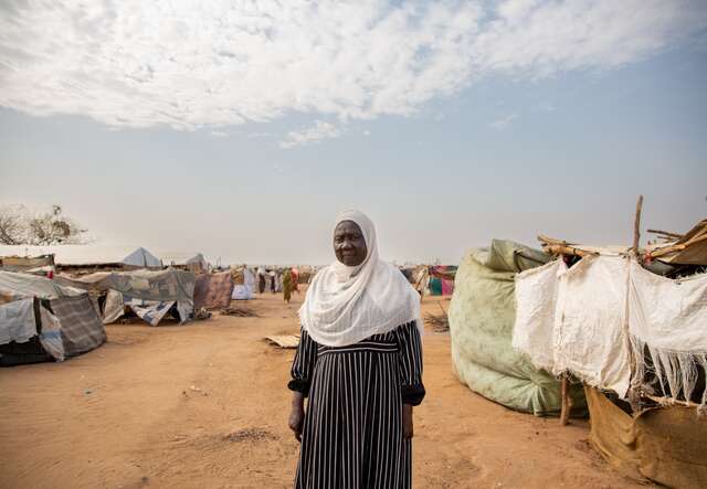 Eine Frau steht vor ihrer provisorischen Unterkunft in einer Notunterkunft für Binnenvertriebene.