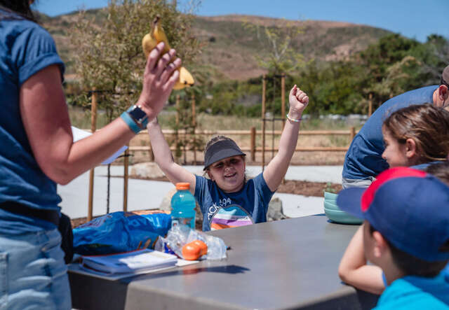 율리아의 딸이 그룹 활동중 두 팔을 위로 번쩍 들어올리며 기뻐하고 있습니다.
