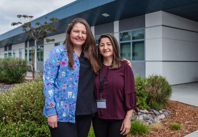 두 여성이 나란히 서서 카메라를 바라보며 웃고 있습니다