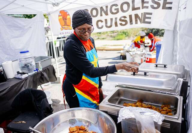 A woman wearing a hijab and an apron in front of hot plates with food