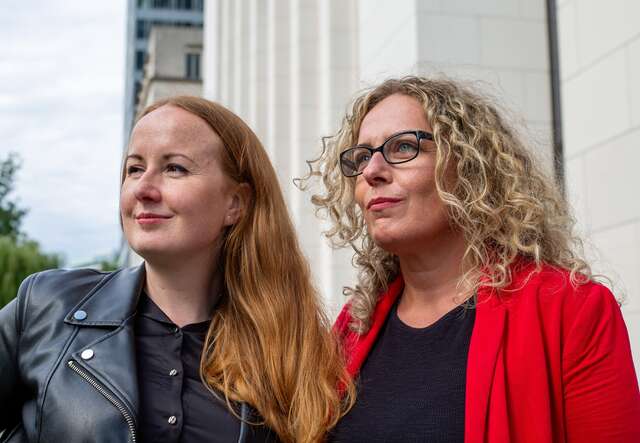 Zwei Frauen stehen nebeneinander im Freien und blicken in die Ferne