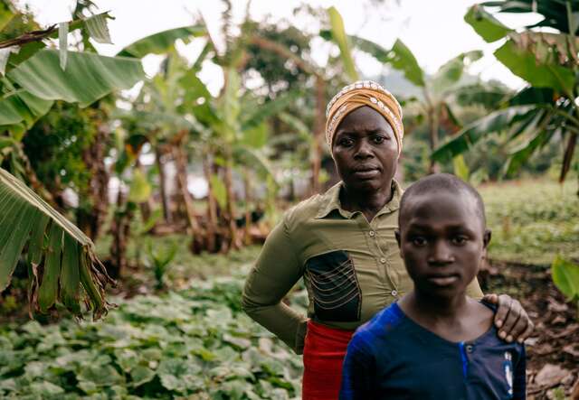 A mother and son pose for a portrait outside of their home in the DRC.