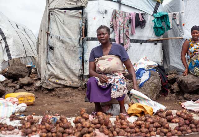 A woman sells potatoes outside of her shelter in a camp for displaced people in the DRC.