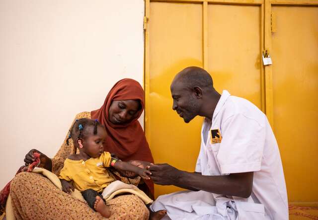 Ein IRC-Gesundheitsmitarbeiter untersucht ein junges Mädchen auf Anzeichen von Unterernährung.