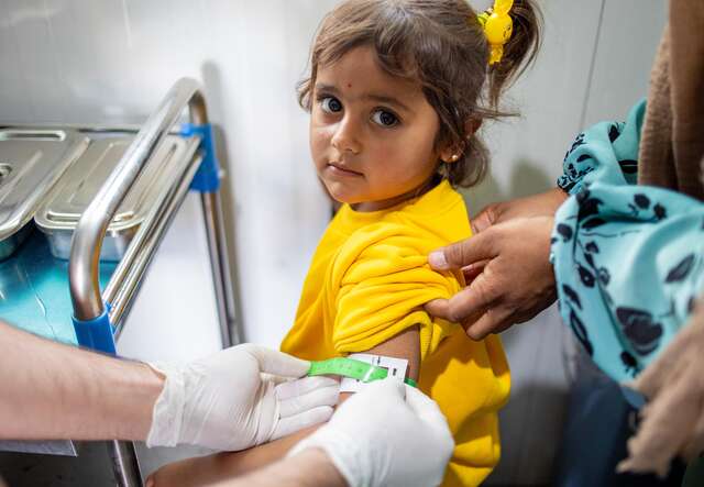 Ein Mädchen in gelbem Shirt wird von medizinischem Personal untersucht.