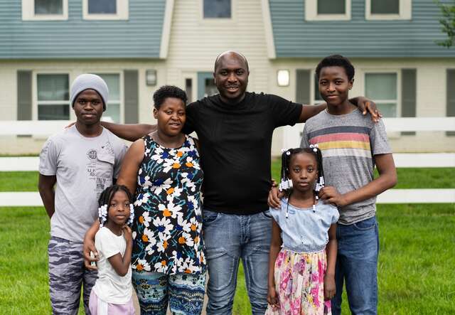 A refugee family from Burundi and Zimbabwe proudly stand outside of their new home in Louisville, Kentucky.