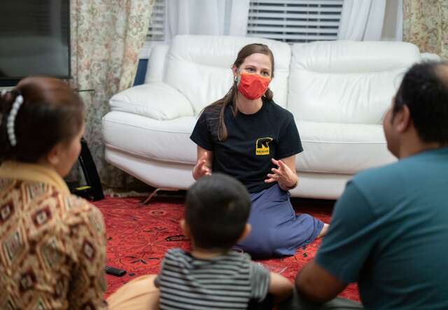 IRC worker sitting on family's floor providing guidance