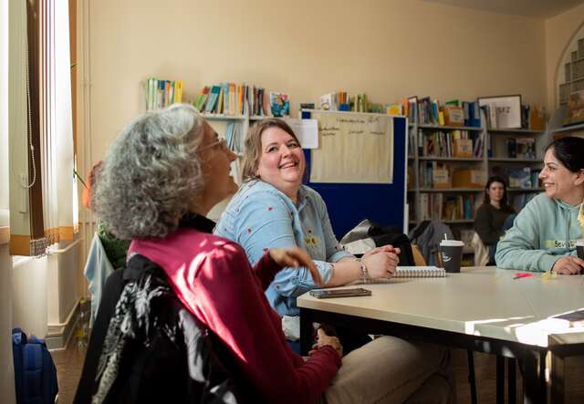 Drei Personen sitzen an einem Tisch und unterhalten sich.