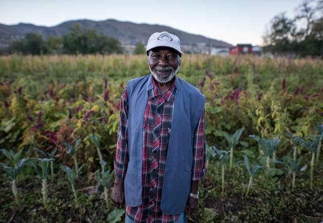 Omar, a refugee from Sudan, stands proudly in front of his farm in Salt Lake City, Utah.