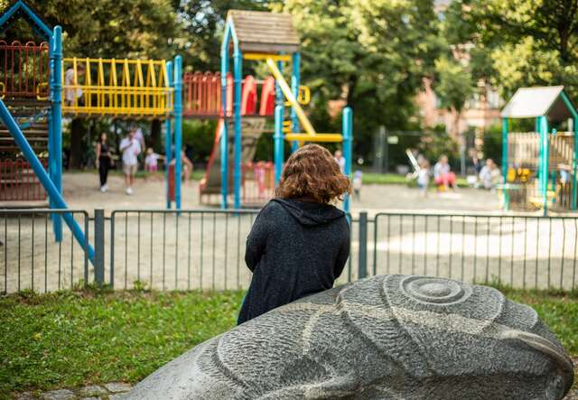 A woman watches her child play on a playground in Germany.