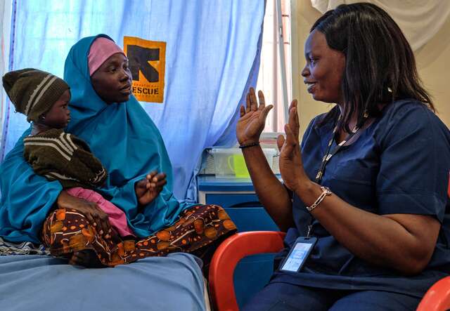 An IRC health care member screens a young girl for signs of malnutrition in Nigeria.