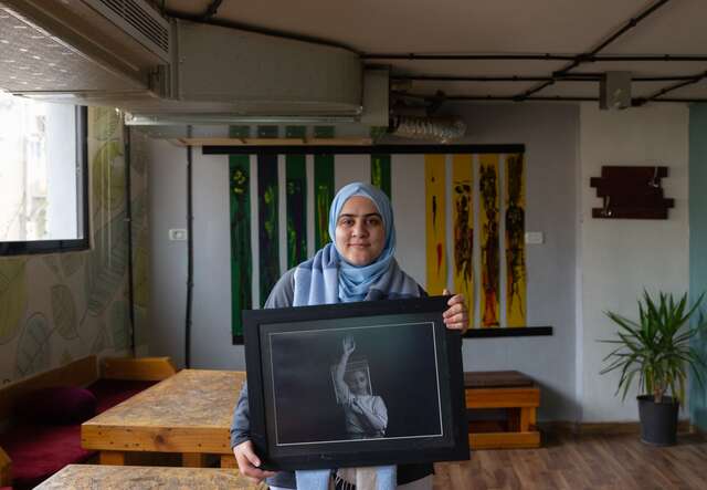 A Syrian refugee and photographer shows off her artwork at a studio in Amman, Jordan.