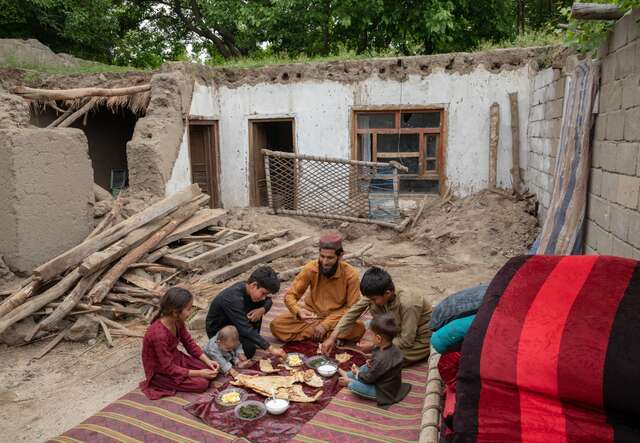 Azim and his family eat lunch together in the ruins of their home which was destroyed by severe flooding.