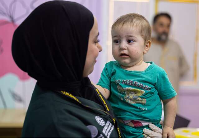 Duha hält ein Kind im Arm, nachdem sie es in der IRC-Klinik medizinisch untersucht hat.