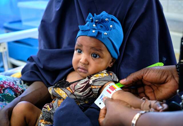 Ein kleines Kind wird von einem IRC-Mitarbeiter in Nigeria auf Unterernährung untersucht.