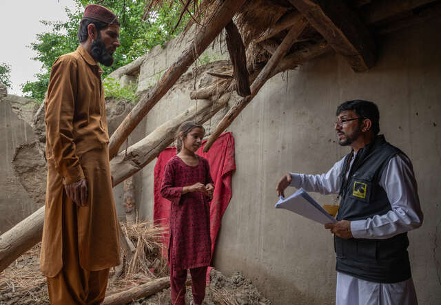 En pappa och hans dotter står vid sitt hem i Afghanistan där taket gått sönder. De pratar med RESCUE:s medarbetare.