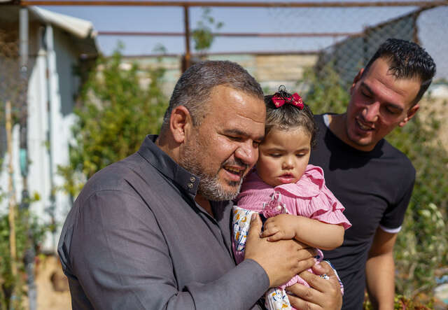 En pappa och en farfar kramar om en flicka i ett flyktingläger i Jordanien där RESCUE ger humanitärt stöd.