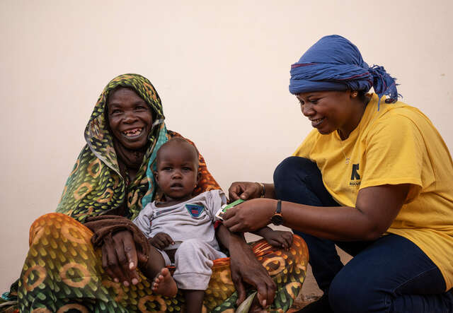 En liten pojke sitter i sin mormors knä och får behandling mot undernäring av RESCUE:s personal i Tchad.