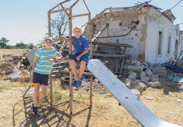 두 소년이 최근 공격으로 파괴된 우크라이나의 폐허가 된 놀이터에서 놀다가 사진을 찍기 위해 포즈를 취하고 있습니다.