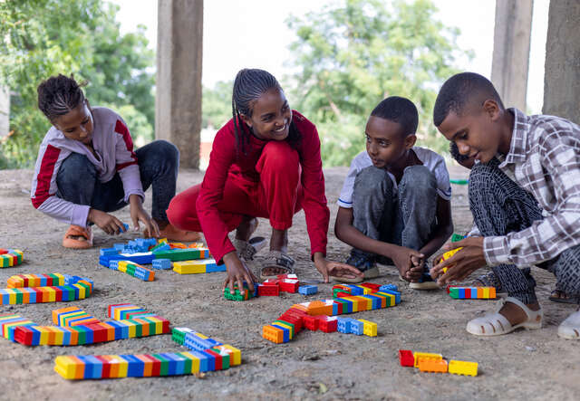 Fyra elever sitter på huk och arbetar med klossar vid sin skola i Etiopien.