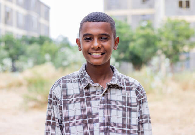 En pojke i Etiopien ler mot kameran. Han är en av många unga som fått tillgång till utbildning genom RESCUE.