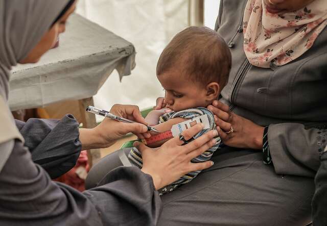 A Palestinian child is treated for malnutrition by an IRC staff member in Gaza.