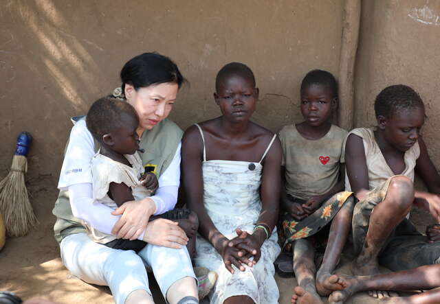 국제구조위원회 홍보대사 오민애 배우가 이두아의 집 앞에서 함께 앉아 이야기를 나누고 있습니다.