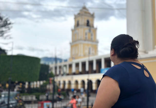 Woman looking at a building, we see her from the back.