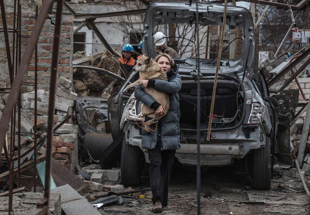 En kvinna i Mykolajiv, Ukraina, bär sin skadade hund efter en rysk drönarattack mot ett bostadsområde.