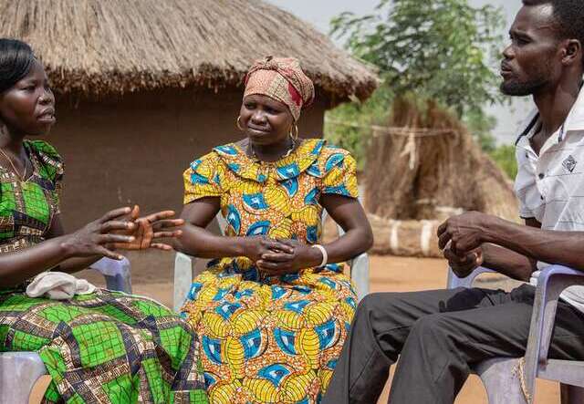 Community members talking together in a rural village setting.
