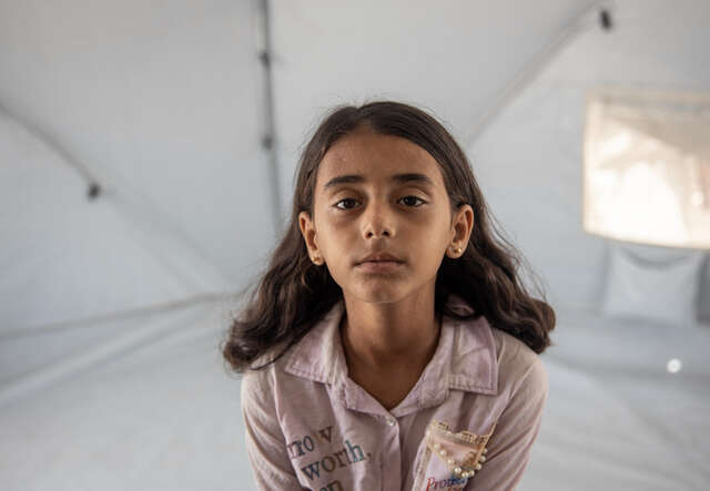 Ruba, a ten year old Palestinian girl, sits in a tent.