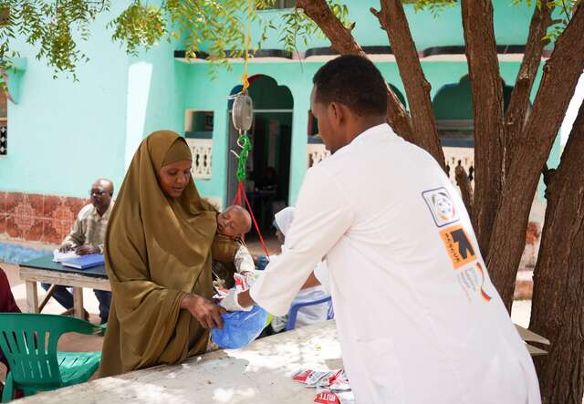 Eine Mutter mit Kind lässt es in einer Gesundheitseinrichtung wiegen.