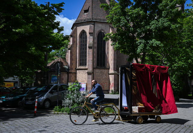 Bashar rides a bike pulling his mobile theatre set