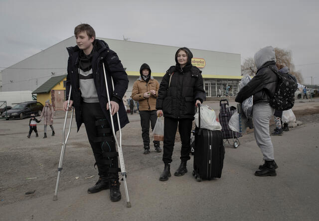 A family flee Ukraine with a young man using crutches