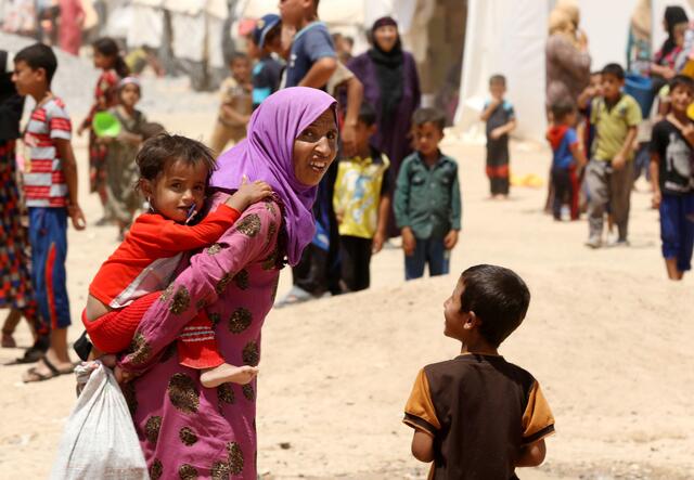 Iraqi displaced women and children, who fled the violence in the northern city of Mosul, walk at the Dibaga camp on July 16, 2016 in Makhmur, about 280 kilometres (175 miles) north of the capital Baghdad.