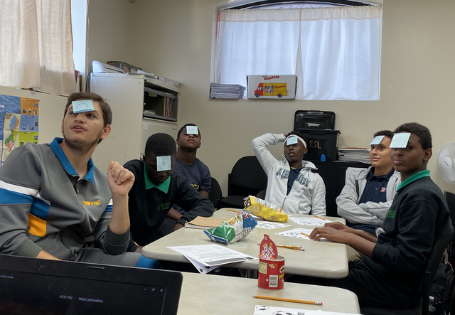 students gathered at a table playing a post-it game