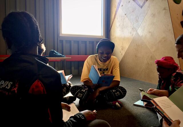 Group of five women reading together in a circle.