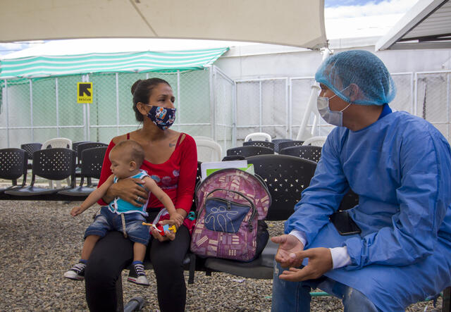 A health worker speaks with a mother holding her baby at a migrant center on the Colombian border with Venezuela, where the IRC is providing medical services.