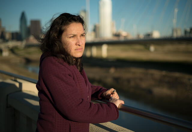 Valentina, a refugee from El Salvador, stands on a bridge in Dallas, TX, and looks out over the water.