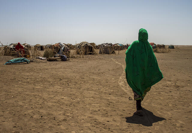 A woman looks into the distance at the temporary shelter in a refugee camp in Ethiopia.