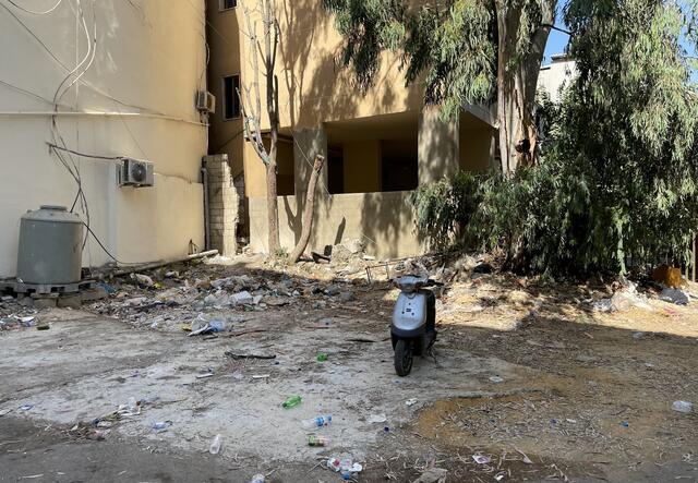An empty lot filled with litter and one motorbike