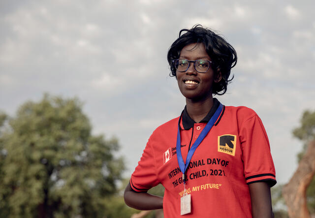 Wearing a t-shit with an IRC logo, a woman smiles outside with her hand on her hip. 