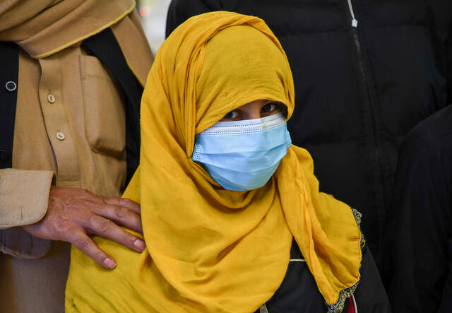 A close up of a young woman wearing a mask and a hijab