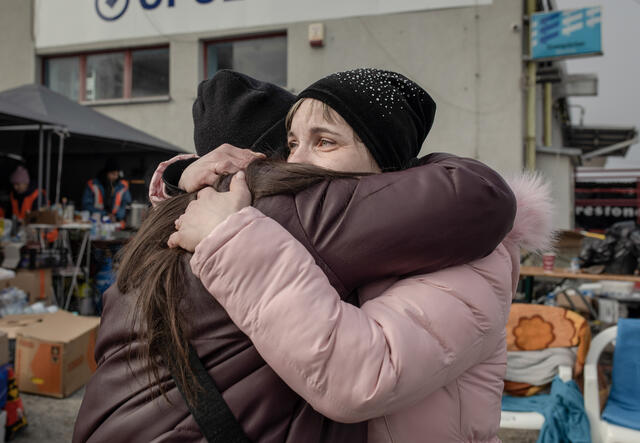 Two women in winter clothes hug.