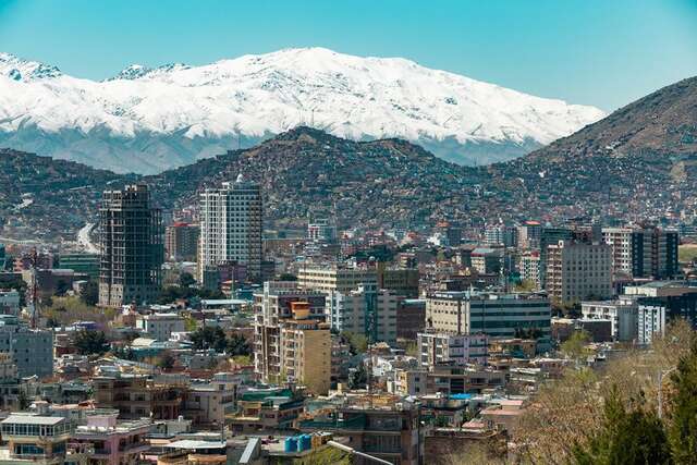 A city surrounded by hills and snow covered mountains