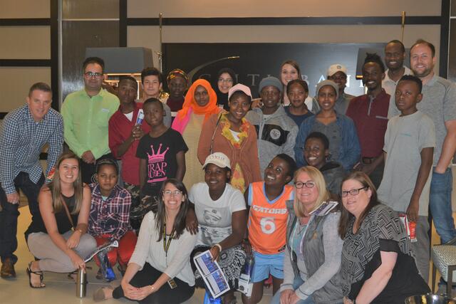 Refugee youth gathering with IRC volunteers posing for a photo.