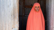 Portrait of 22 year old Misra, an IDP in Ethiopia's Qoloji camp, standing in front of a makeshift classroom
