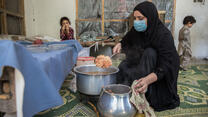 Mariam finalizes the dish presented during her cooking class and prepares to serve it to the participants: Afghan women and children.