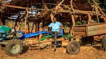 A man sits on a large tractor outside in Zimbabwe.